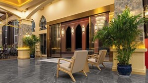A lobby with a reception desk, seating area, and a large potted plant. - Taimei Holiday Hotel (Chongqing)