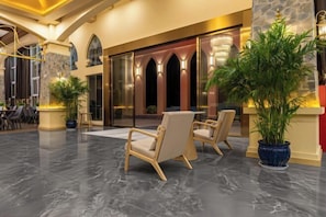 A lobby with a reception desk, seating area, and a large potted plant. - Taimei Holiday Hotel (Chongqing)