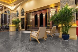 Um lobby com balcão de recepção, área de estar e uma grande planta em vaso.