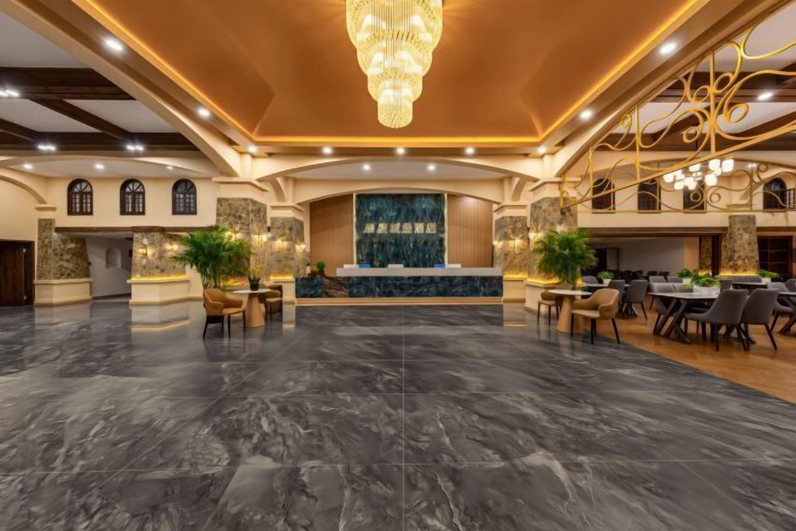 A spacious lobby with a marble floor, a reception desk, and a chandelier.