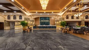 A spacious lobby with a marble floor, a reception desk, and a chandelier.