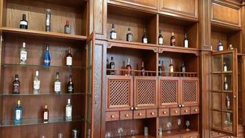 A wooden liquor cabinet with multiple shelves and drawers, containing various bottles and glasses.