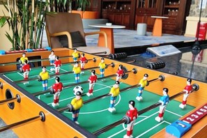 Una mesa de fútbol de mesa con jugadores con uniformes rojos y amarillos, ubicada en un campo verde con indicador de puntuación.