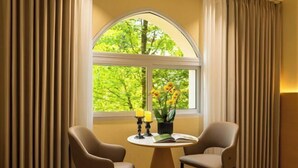 A room with a round table, two chairs, a window with curtains, and a vase with flowers. - Taimei Holiday Hotel (Chongqing)