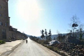 Una carretera con un edificio a la izquierda y árboles a la derecha.