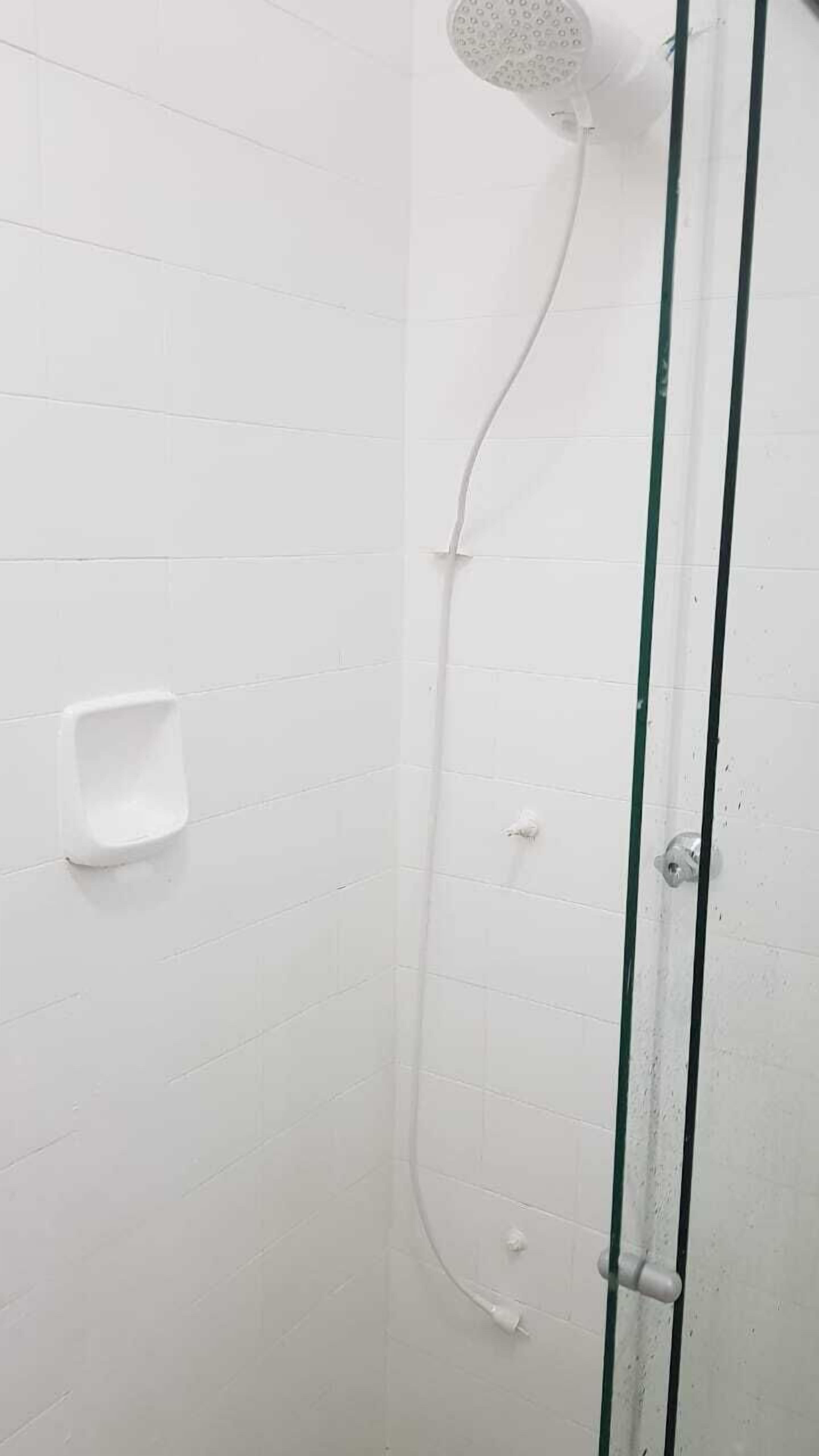 Eine Dusche mit Handbrause, Duschwandhalterung und ein fest montiertem Ventil.