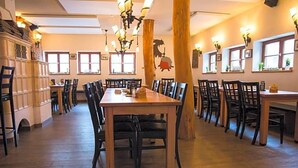 Un comedor con varias mesas y sillas, suelo de madera y luminarias fijadas a la pared.
