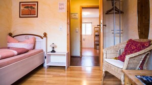 Un dormitorio con una cama, una mesita de noche, una silla y una puerta que da a un baño.