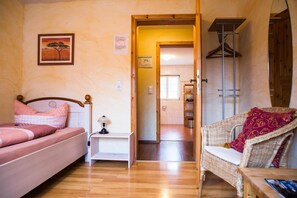 A bedroom with a bed, a nightstand, a chair, and a door leading to a bathroom. - Landhotel Im Hexenwinkel (Wiernsheim)