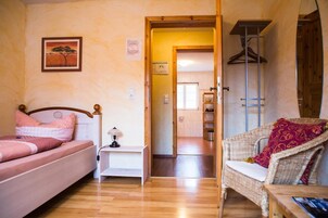 Un dormitorio con una cama, una mesita de noche, una silla y una puerta que da a un baño.