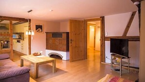 Ein gemütliches Wohnzimmer mit Holztisch, Sofa, Kamin und Fernseher.