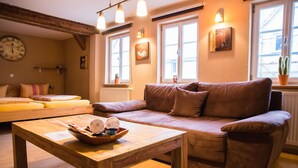 Una sala de estar acogedora con un sofá marrón, una mesa de centro de madera y un reloj en la pared.