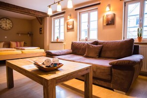 A cozy living room with a brown sofa, wooden coffee table, and a clock on the wall. - Landhotel Im Hexenwinkel (Wiernsheim)