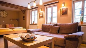 Ein gemütliches Wohnzimmer mit braunem Sofa, Couchtisch aus Holz und einer Uhr an der Wand.