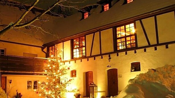 Un edificio con fachada tradicional, múltiples ventanas y suelo cubierto de nieve.