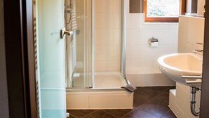 Un baño con cabina de ducha de vidrio, lavabo y ventana.