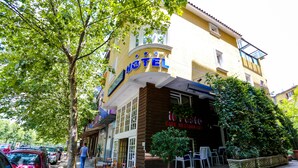 Hotel com fachada amarela, área de estar externa e restaurante café.