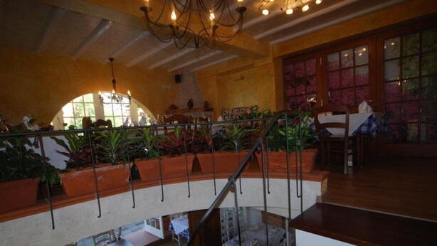 Uma área de refeições em vários níveis, com escada, plantas em vasos e um candelabro.