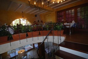 Un espacio para comer con varios niveles, una escalera, plantas en macetas y un candelabro.