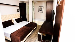 Quarto de hotel com uma cama, uma escrivaninha e uma televisão.