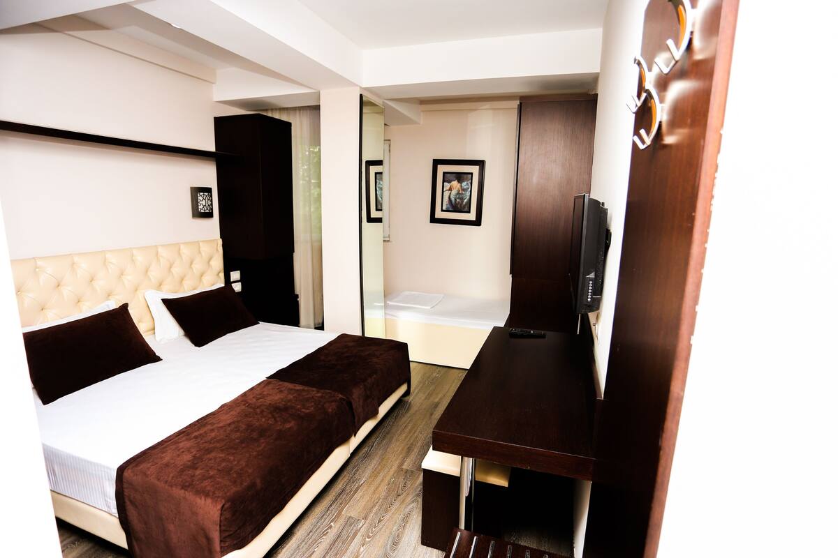 A hotel room with a bed, a desk, and a TV.