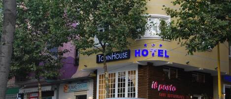 A hotel with a sign reading 'TNHOUSE HOTEL' and a 'KLINIKE DENTARE' adjacent to it.