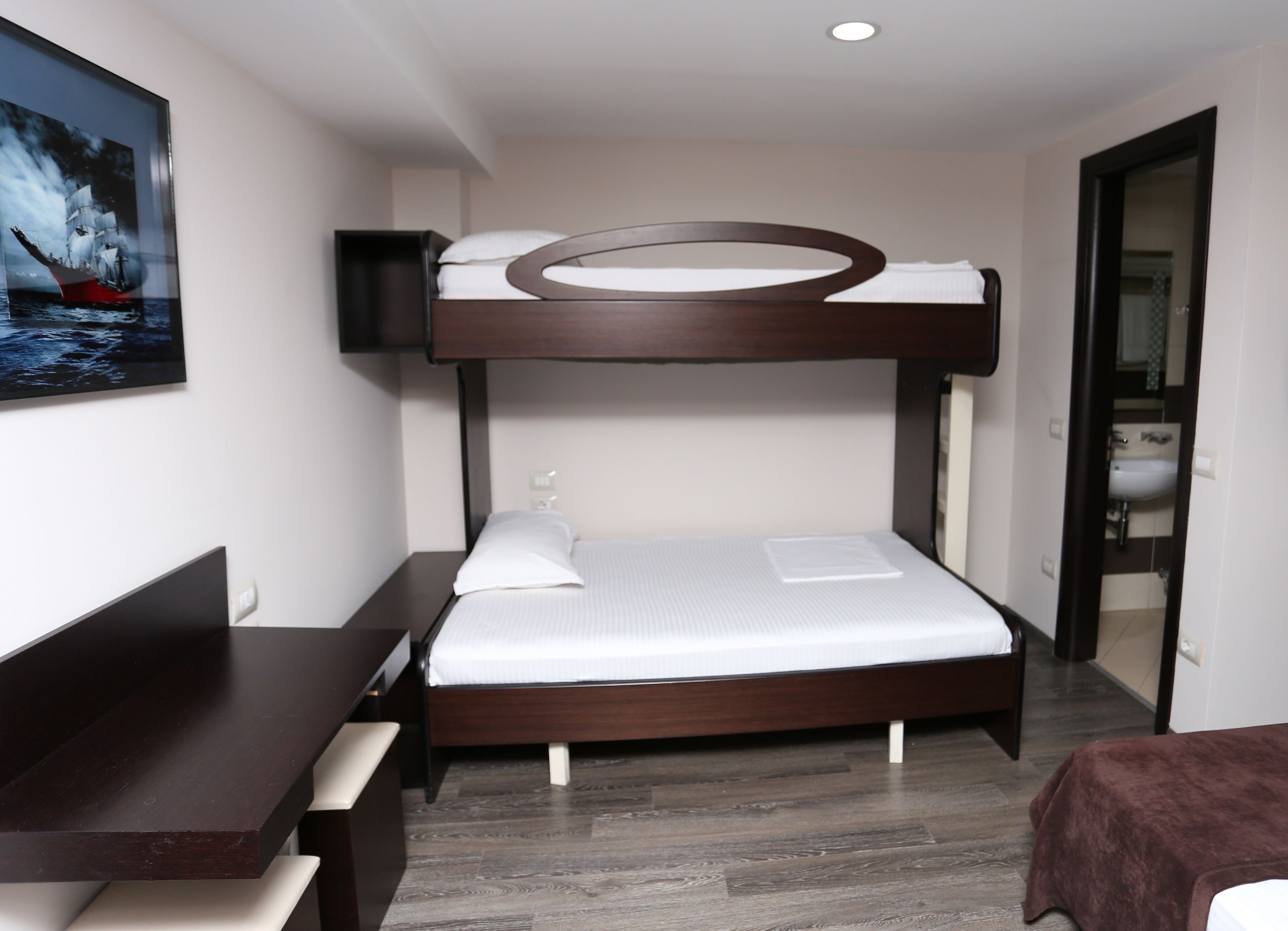 A bunk bed with a desk and a bed with a pillow and a small white object on it.
