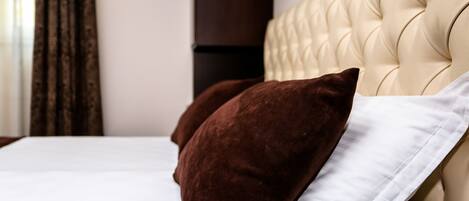 Uma cama com cabeceira estofada, um travesseiro branco e um marrom.