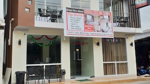 A multi-story hostel with balconies, a reception area, and a sign advertising amenities like private rooms and Wi-Fi. - Top Hostel Samui (Koh Samui)