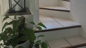 Una escalera con paredes blancas y un farol negro sobre un pedestal blanco.