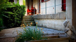 A stone staircase leading to a building with red shutters and a statue in the foreground. - House with independent studio and pool in a village in the heart of the Alpilles (Paradou)