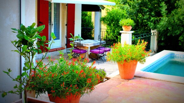 A patio with a pool, outdoor furniture, and potted plants. - House with independent studio and pool in a village in the heart of the Alpilles (Paradou)