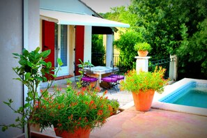 Une terrasse avec une piscine, du mobilier d’extérieur et des plantes en pot.