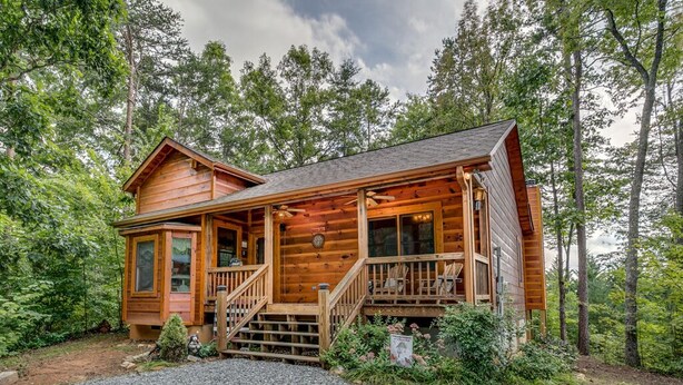 Une cabane en bois avec une véranda, un escalier et une petite terrasse.