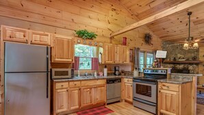Une cuisine de style rustique, avec des éléments en bois, comprenant un réfrigérateur, un four à micro-ondes, une cuisinière et un lave-vaisselle.
