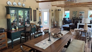 A spacious living room with a wooden dining table, a green cabinet, and a comfortable seating area with a couch and chairs.