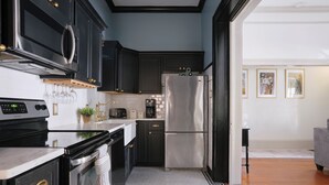 A modern kitchen with dark cabinetry, stainless steel appliances, and a tiled backsplash. - Comfortable Escape 2BR Historic Downtown (Savannah)