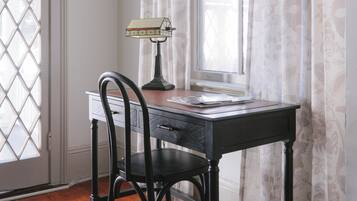 A room with a wooden desk, a chair, a lamp, and a window with curtains.