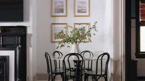 A dining area with a table and chairs, a fireplace, and framed pictures on the wall. - Comfortable Escape 2BR Historic Downtown (Savannah)