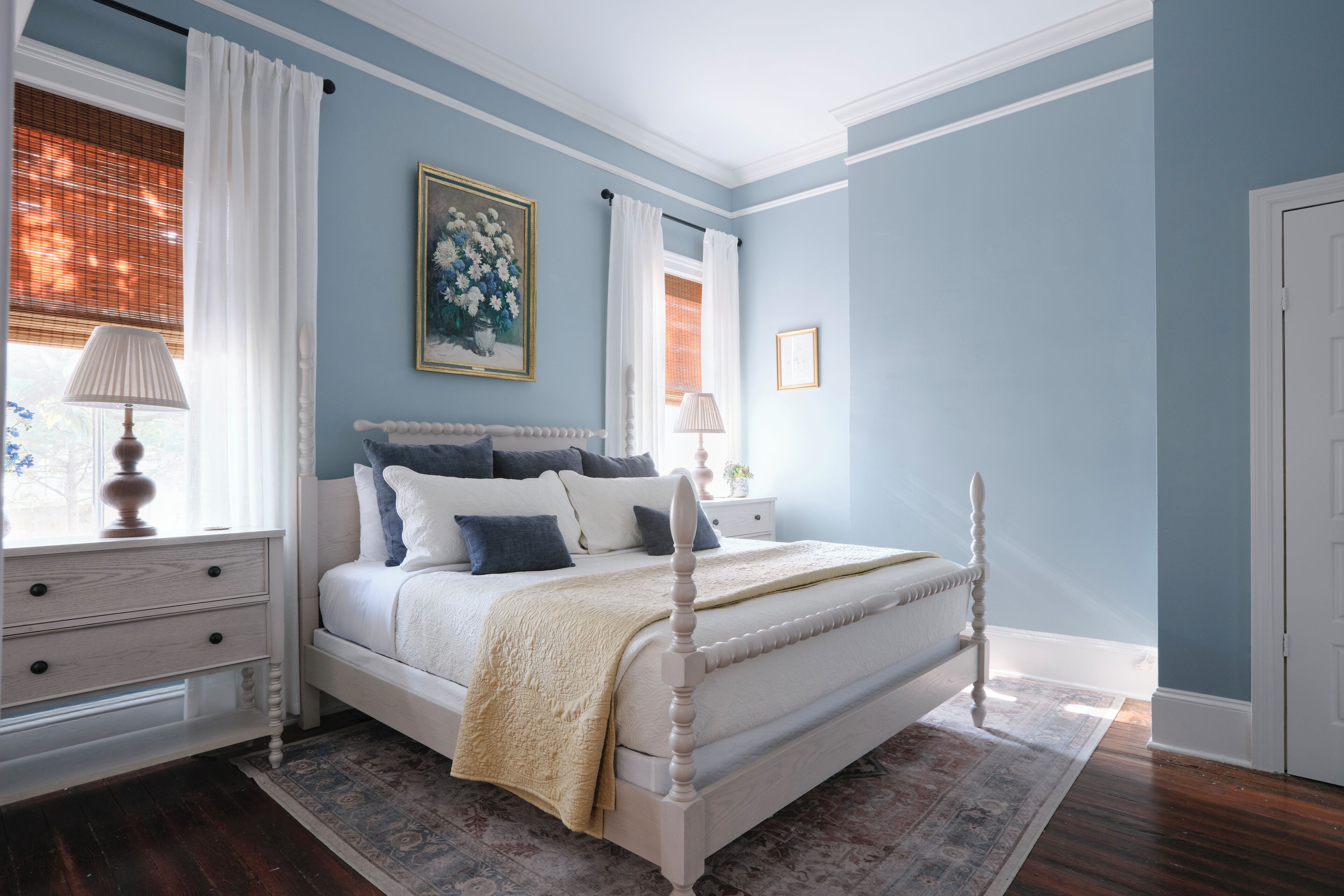 Une chambre à coucher avec un lit à baldaquin, une table de chevet, une commode et une fenêtre avec des rideaux.
