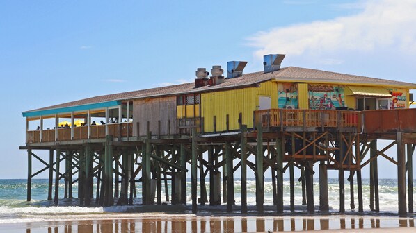 Una estructura de muelle de madera con un restaurante sobre pilotes en el agua.