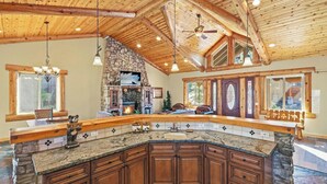 Una cocina amplia con chimenea de piedra, armarios de madera y una isla grande.