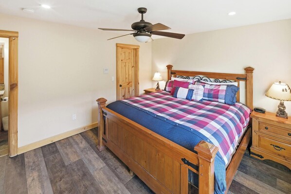 Une chambre à coucher avec un lit en bois, un ventilateur de plafond, une table de chevet avec une lampe et une porte en bois.