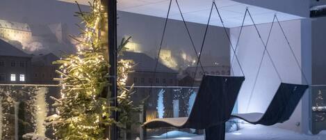 Un espacio exterior cubierto de nieve con un árbol de Navidad y sillas colgantes.