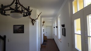 A hallway with white walls, framed pictures, and antler decorations. - Gut Rattelvitz (Gingst)