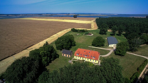 An aerial view of a rural property with a large house, smaller buildings, and surrounding fields. - Gut Rattelvitz (Gingst)