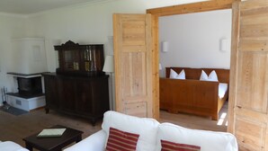 A living room with a white sofa, a dark wooden cabinet, and a wooden bed frame with pillows. - Gut Rattelvitz (Gingst)