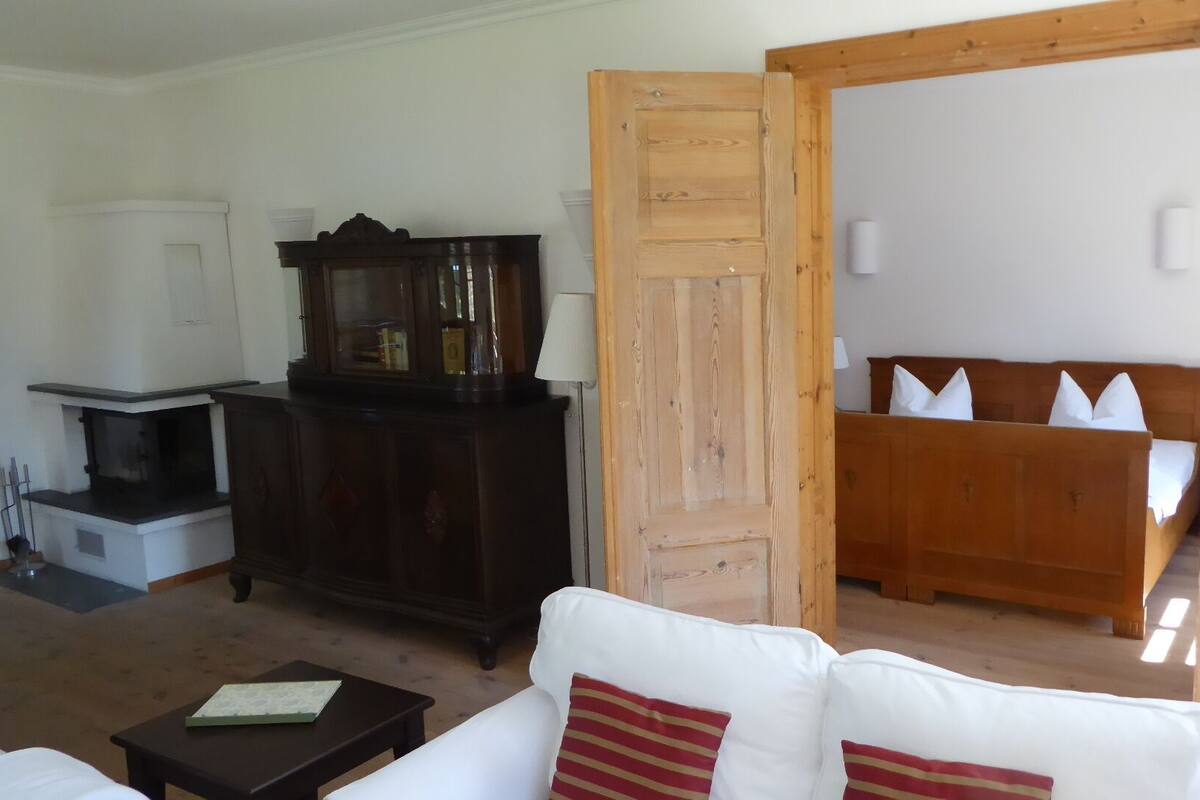 A living room with a white sofa, a dark wooden cabinet, and a wooden bed frame with pillows.