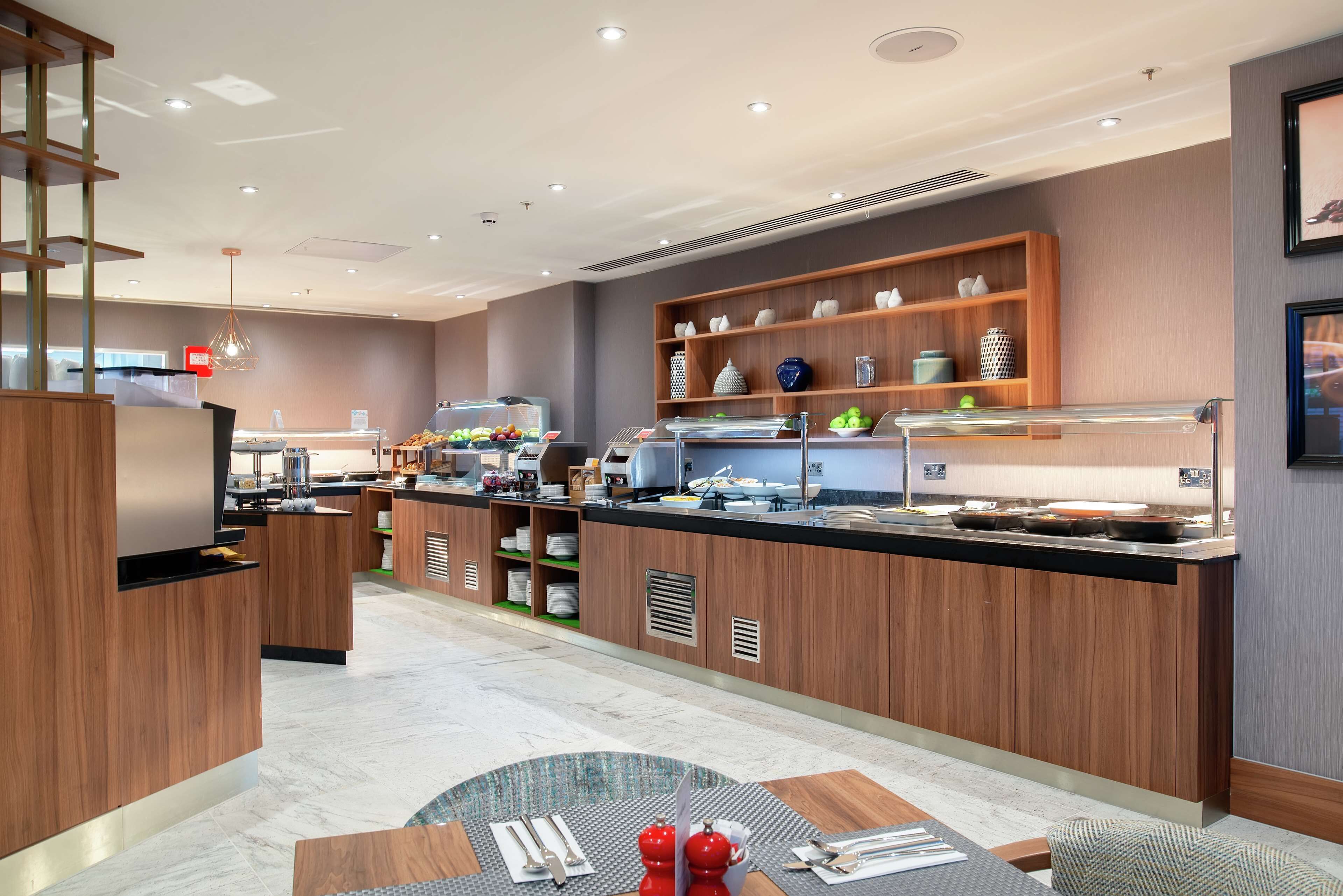 Una cocina de hotel moderna con armarios de madera, una isla central y diversos electrodomésticos.