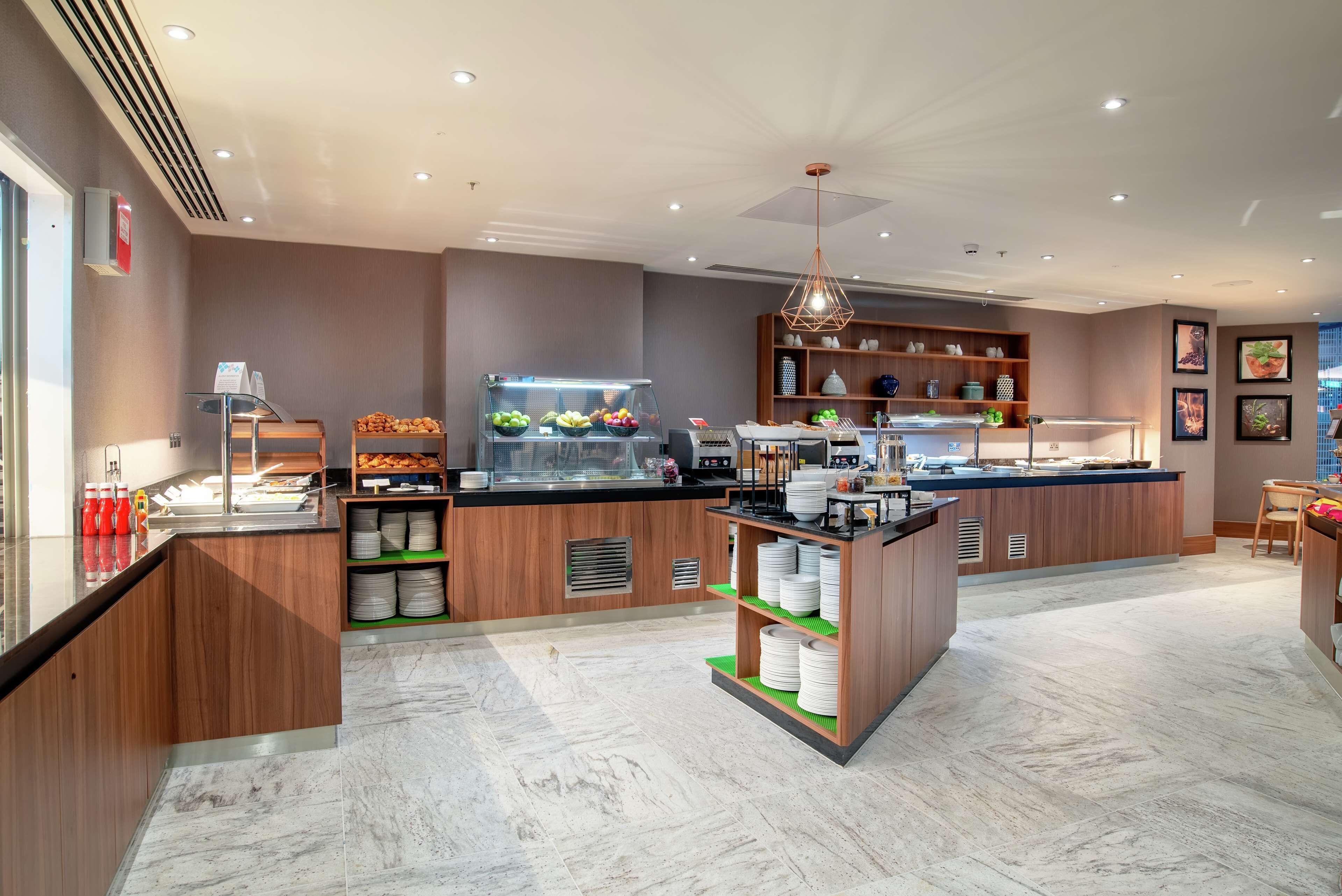 A modern kitchen area with a fruit display, a coffee station, and a seating area.